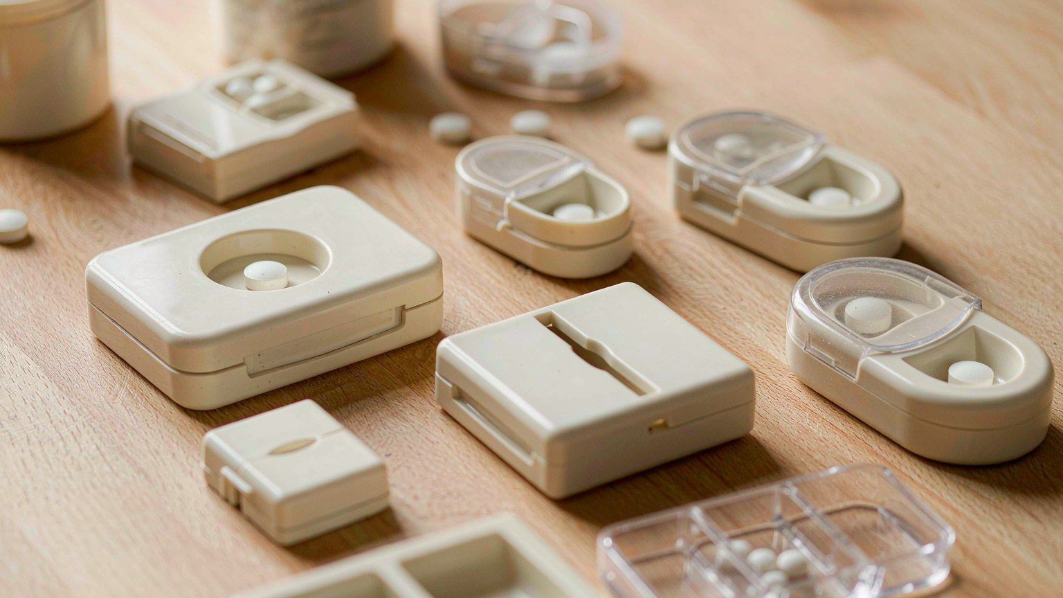 Assortment of different neutral pill splitters and small pill organizers on a clean surface
